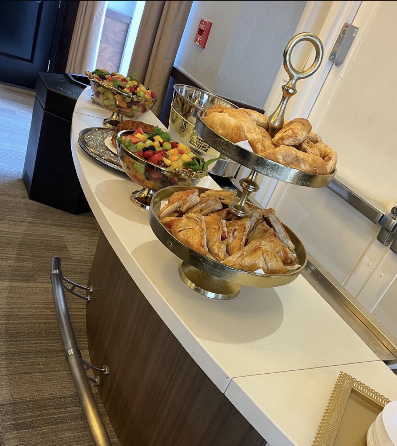 Buffet display of croissants, pastries, and fresh fruit bowls