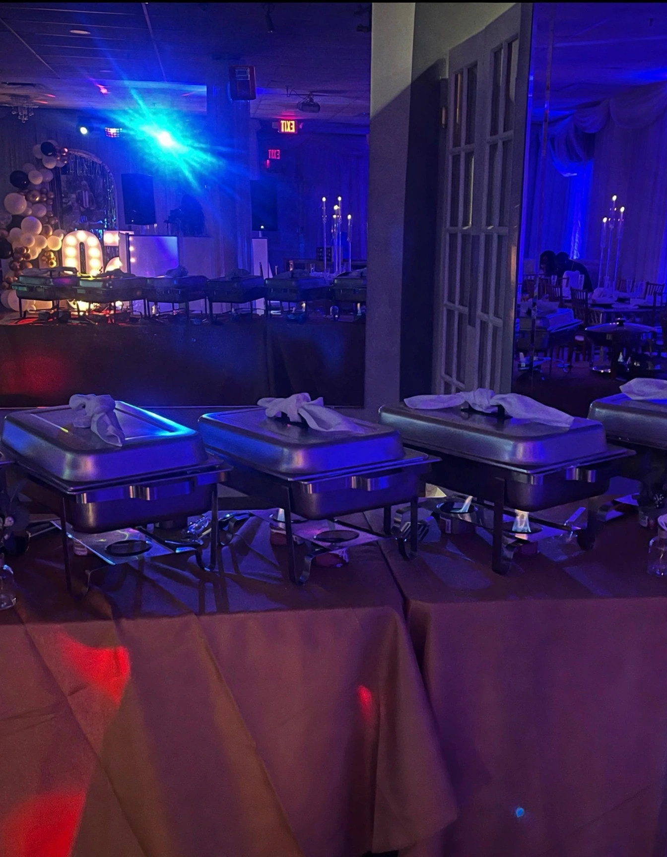 Buffet line with covered chafing dishes under blue event lighting
