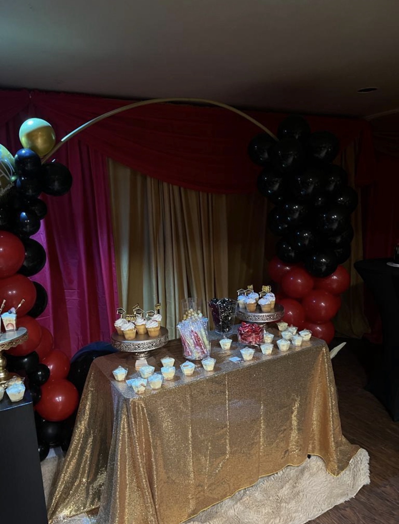 Dessert table framed by a red and black balloon arch