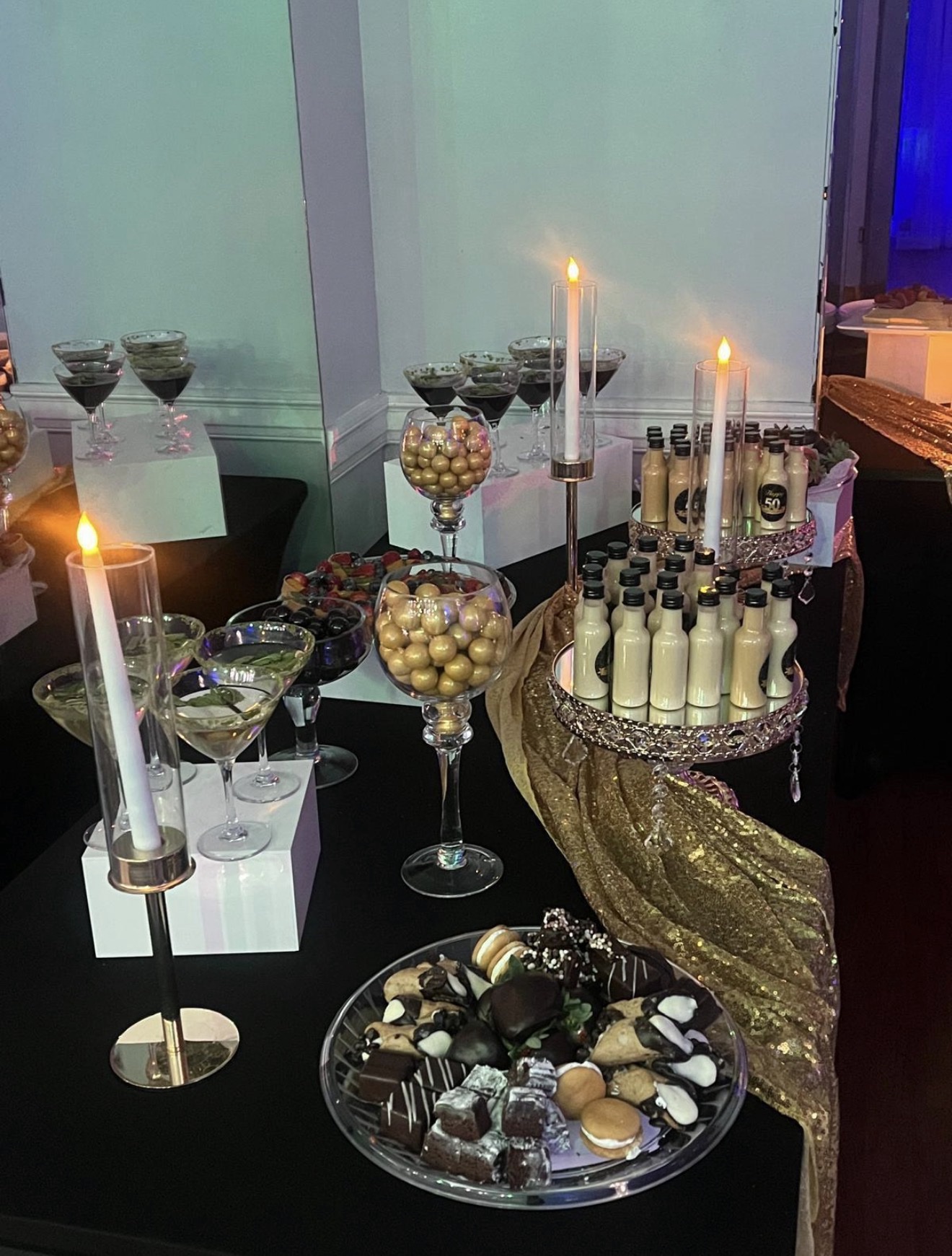 Dessert table with candles, fruit tarts, and treat bottles