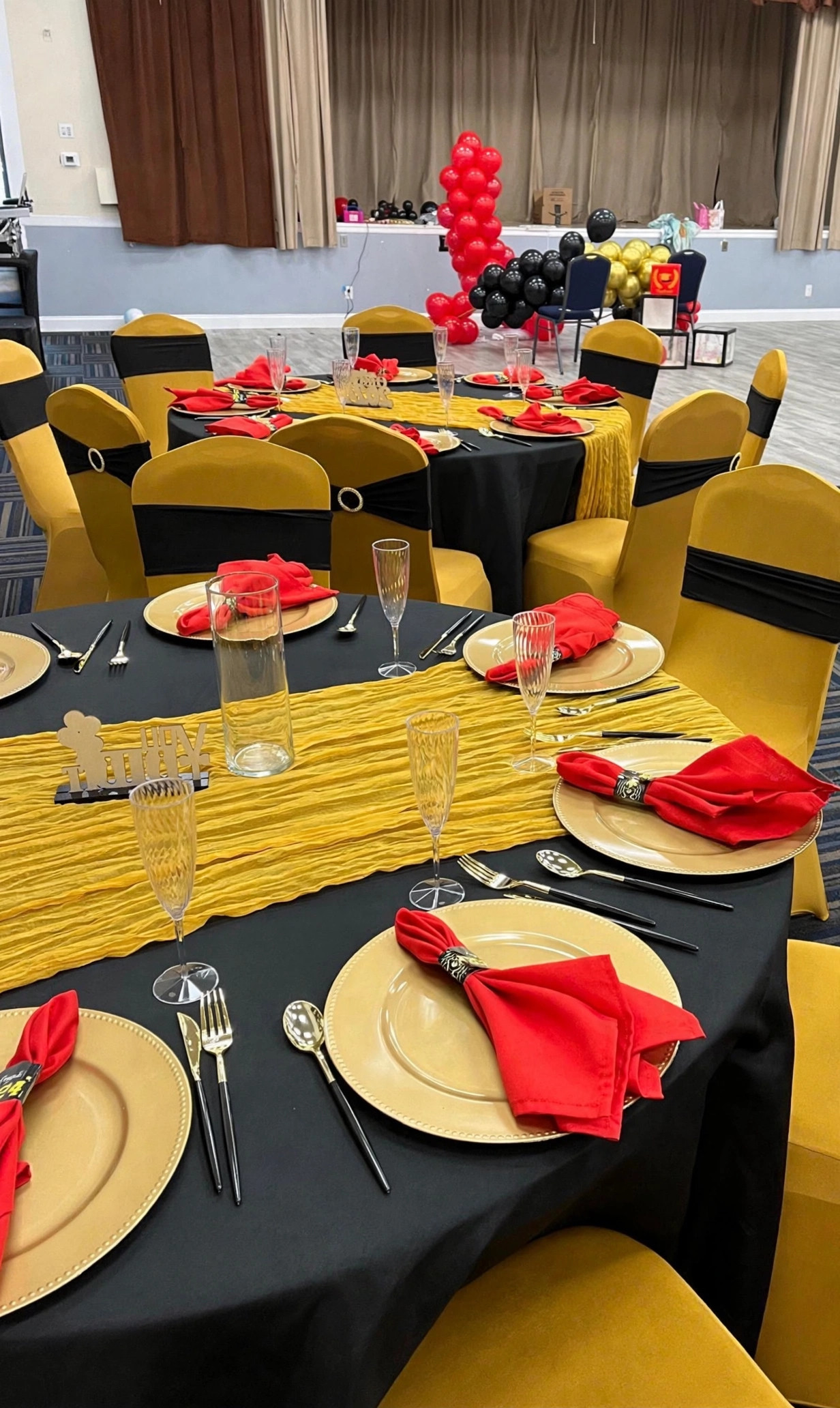 Event hall arranged with red and gold banquet tables