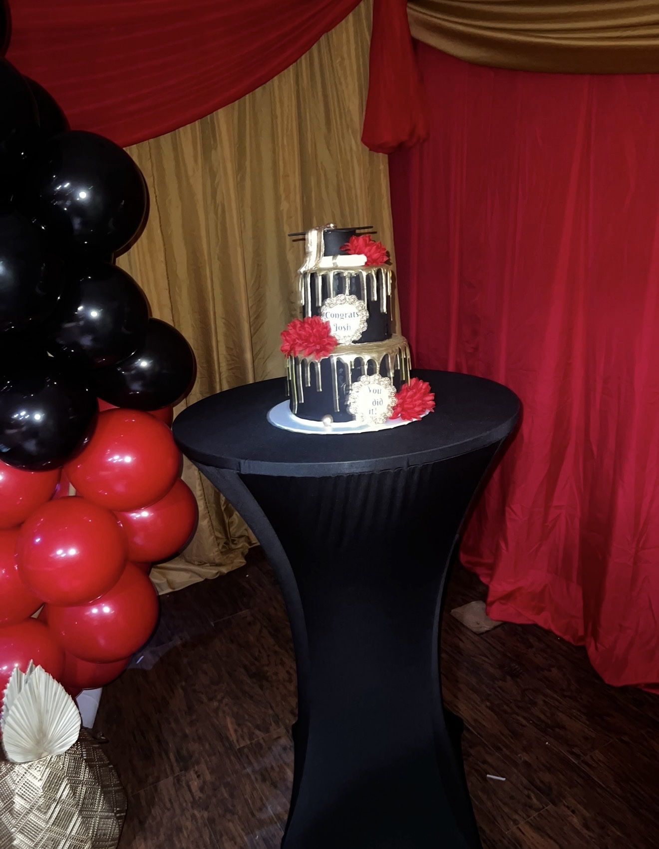 Graduation cake table with black and red balloon decorations