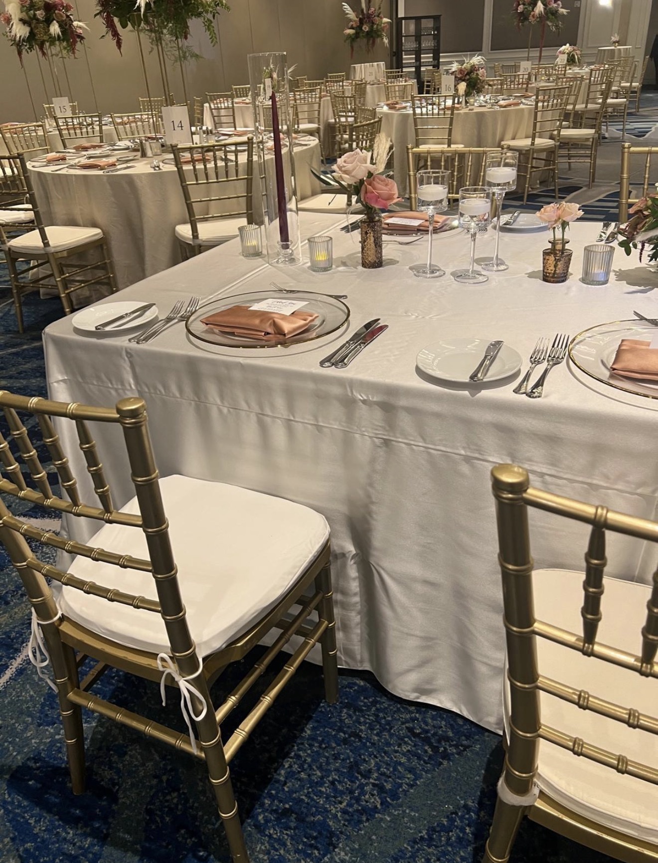 Wedding reception tables with ivory linens and gold chairs