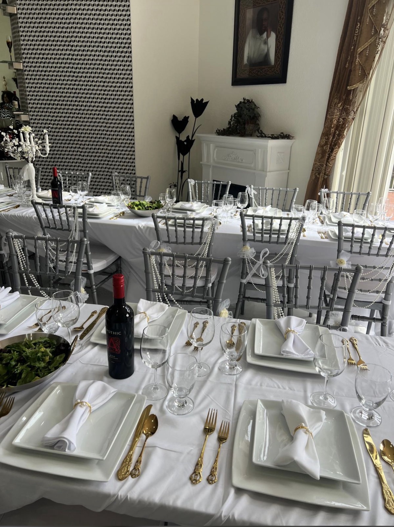 Formal white dinner place settings with gold flatware and chiavari chairs draped with pearls